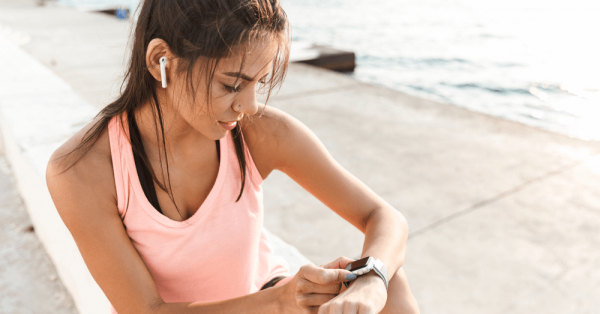 mulher atleta utilizando seu relógio inteligente à beira-mar